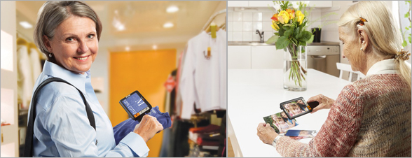 La photo représente une dame utilisant la loupe Explorer 5 dans un magasin de vêtements pour lire une étiquette d'un pull et une autre dame pour regarder de près des photos de famille 